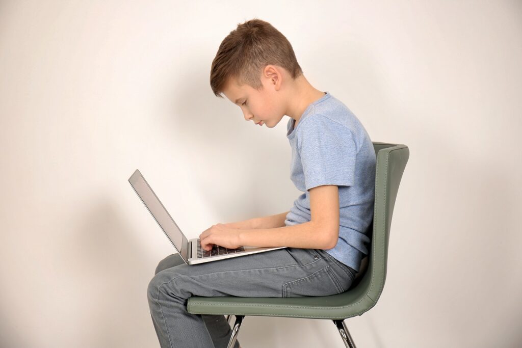 Incorrect,Posture,Concept.,Cute,Schoolboy,With,Laptop,Sitting,On,Chair